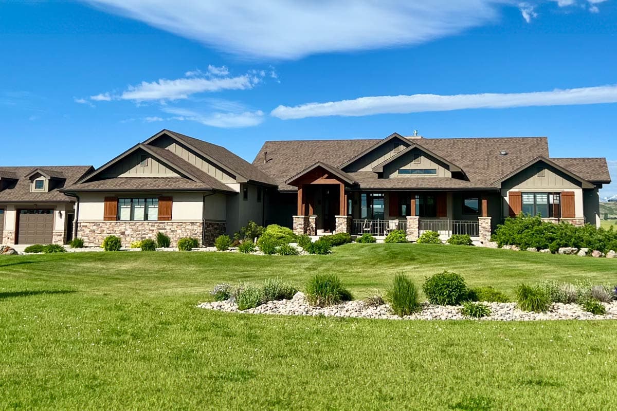 House plan exterior: Ranch-style home with multiple gables, stone accents, covered porch, and attached garage.