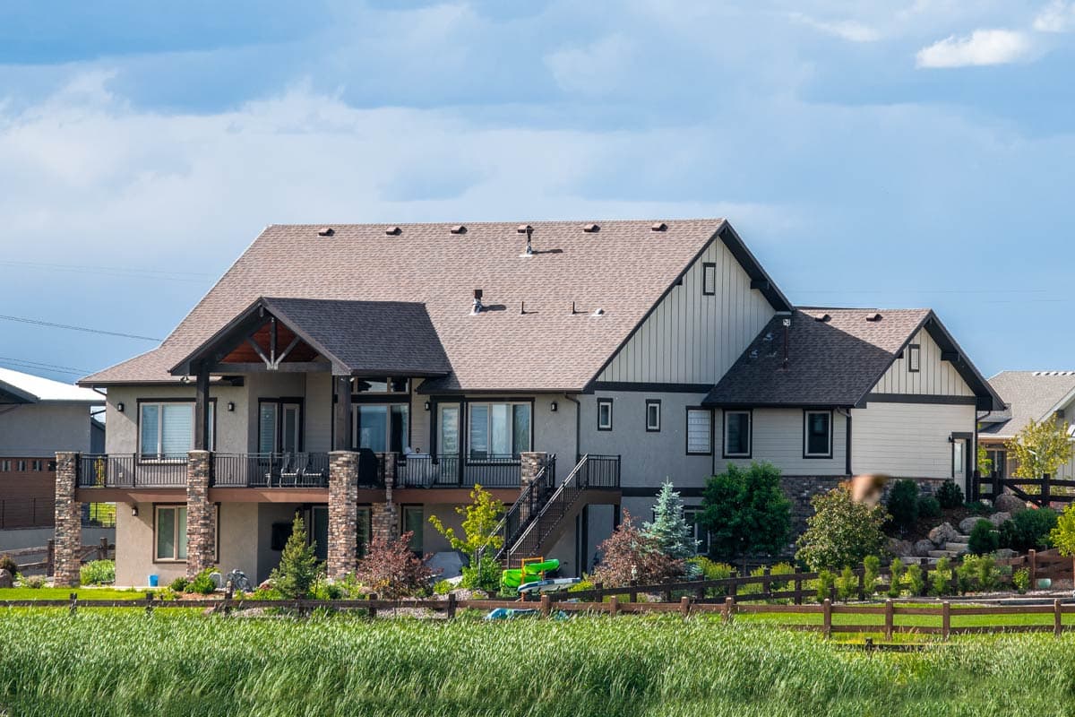 House plan exterior: Two-story Modern Farmhouse with covered porch, gabled rooflines, and stone accents.