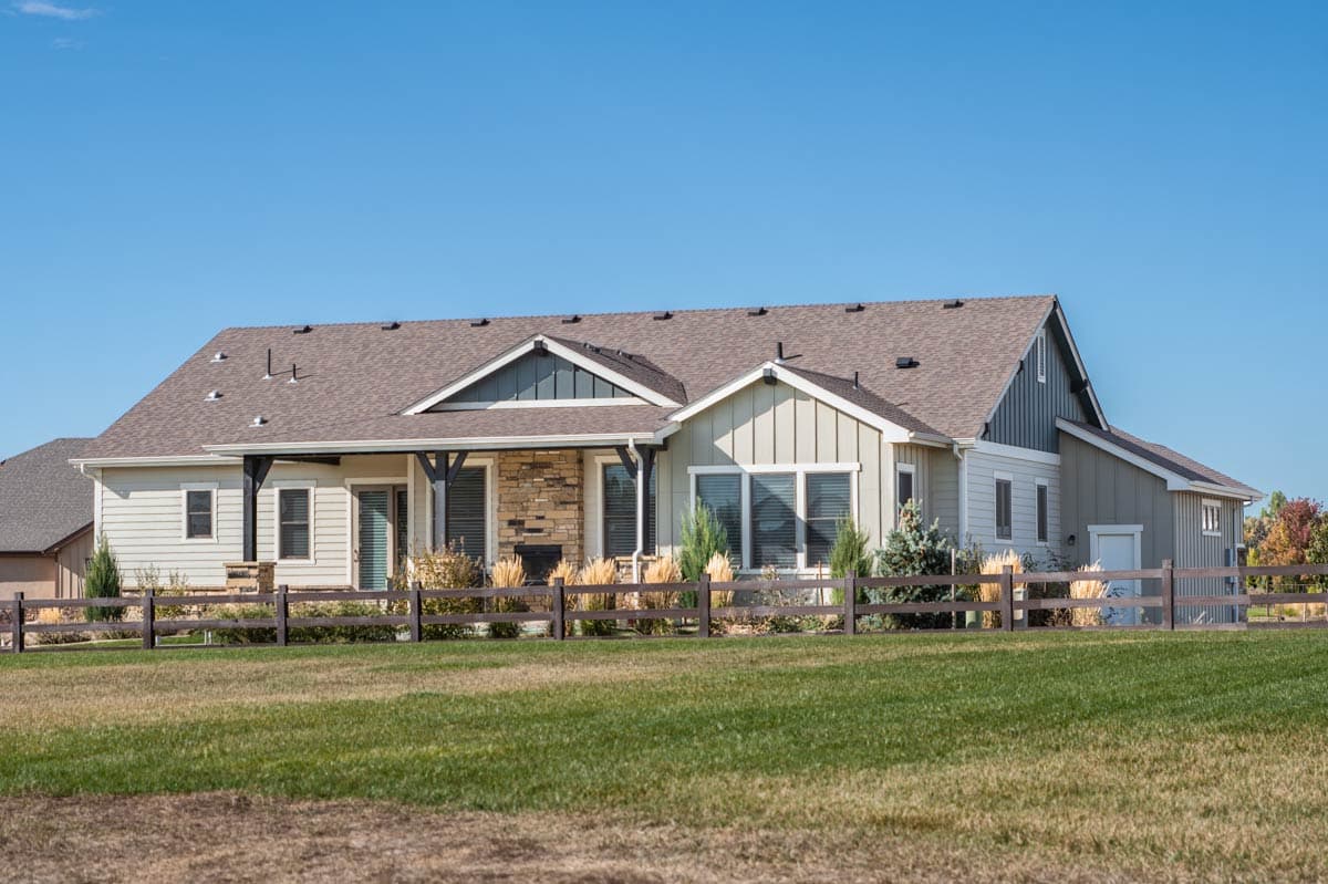 House plan exterior: Ranch style with covered stone porch, gables, dormers, and wood fence.