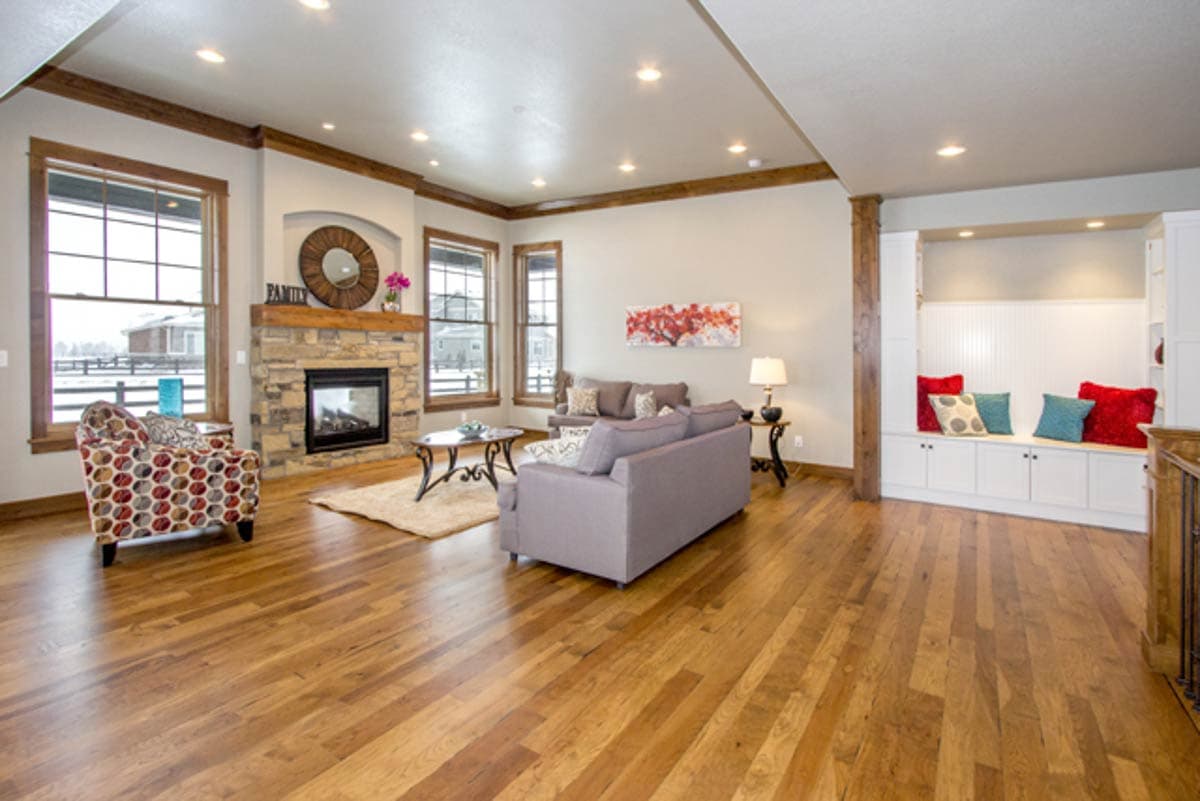 Living room with stone fireplace, built-in seating, two sofas, and hardwood floors.