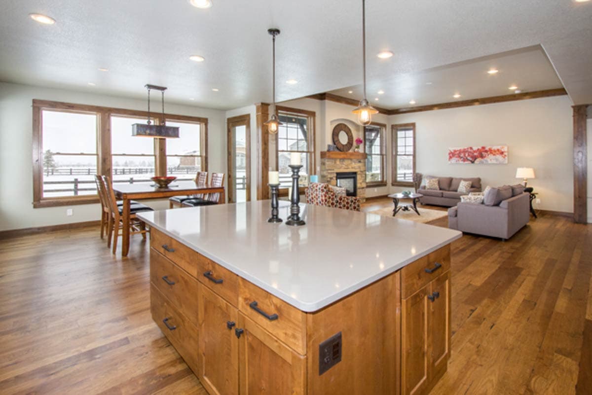 Open concept living area with kitchen island, dining area, and living room featuring a stone fireplace.