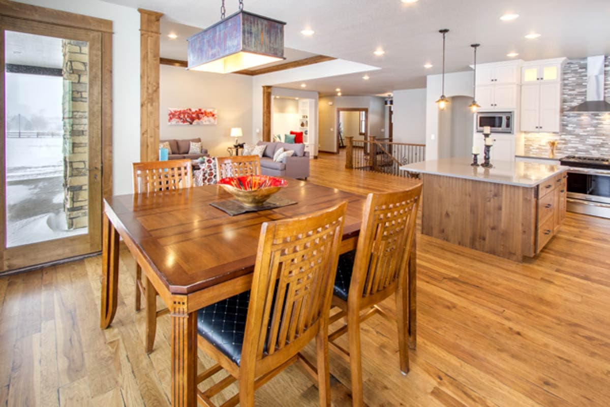 Open concept interior with dining area, great room, and kitchen island. Features wood floors, beams, and stone accents.