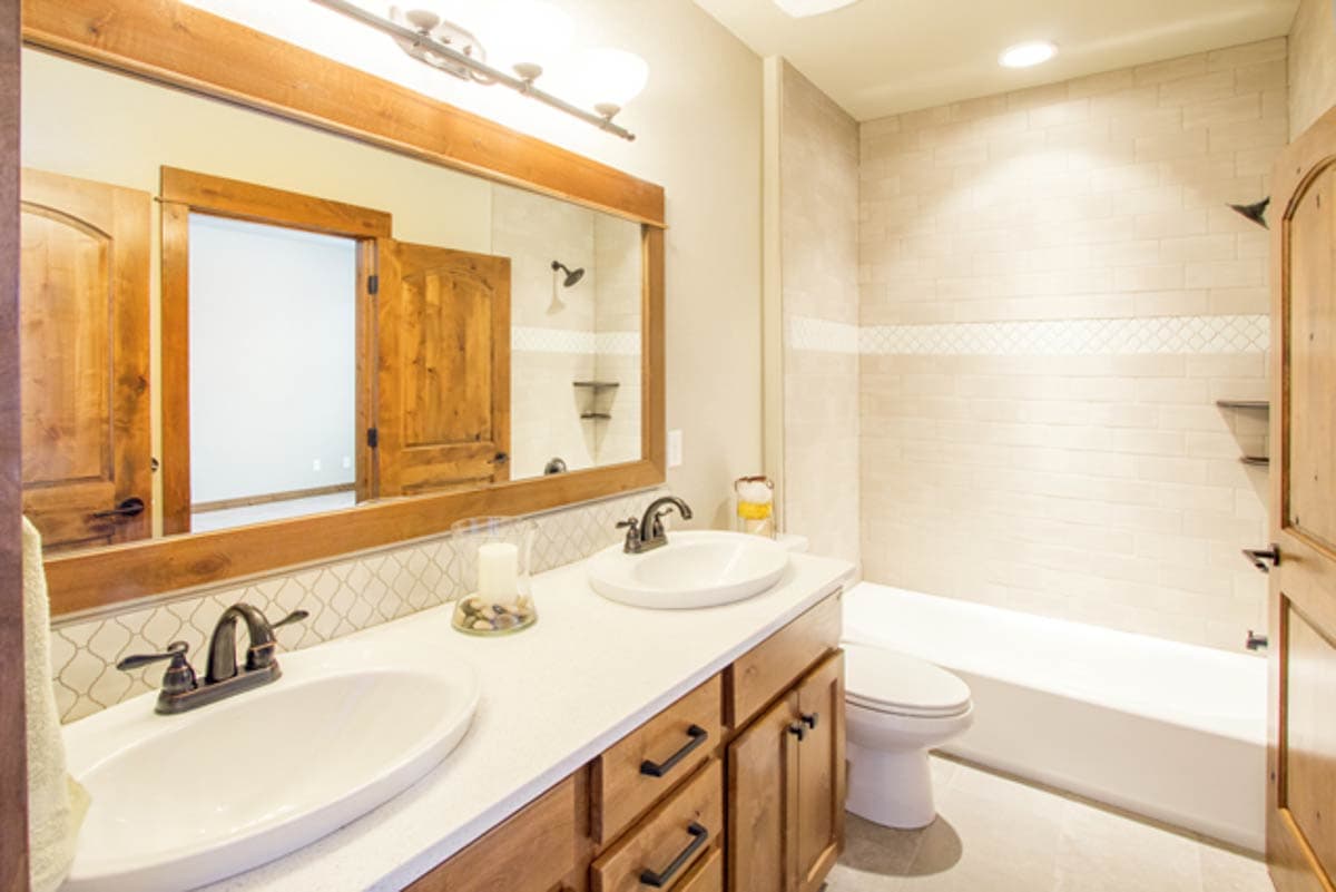 Bathroom with double vanity, wood cabinetry, white countertops, bathtub, and tiled shower.