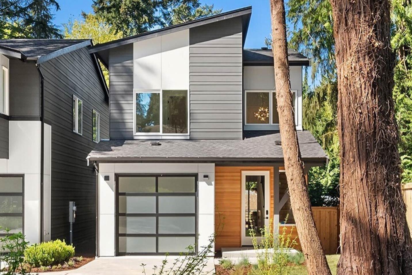 Modern house plan exterior: Two stories, asymmetrical gables, horizontal siding, wood accents, and glass garage door.