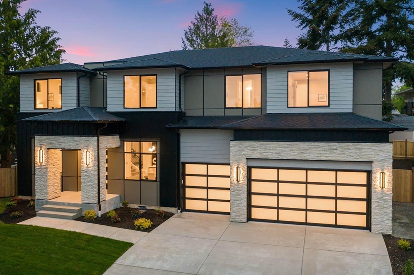Modern two-story house plan exterior with stacked stone entrance, multiple gables, and glass garage doors.