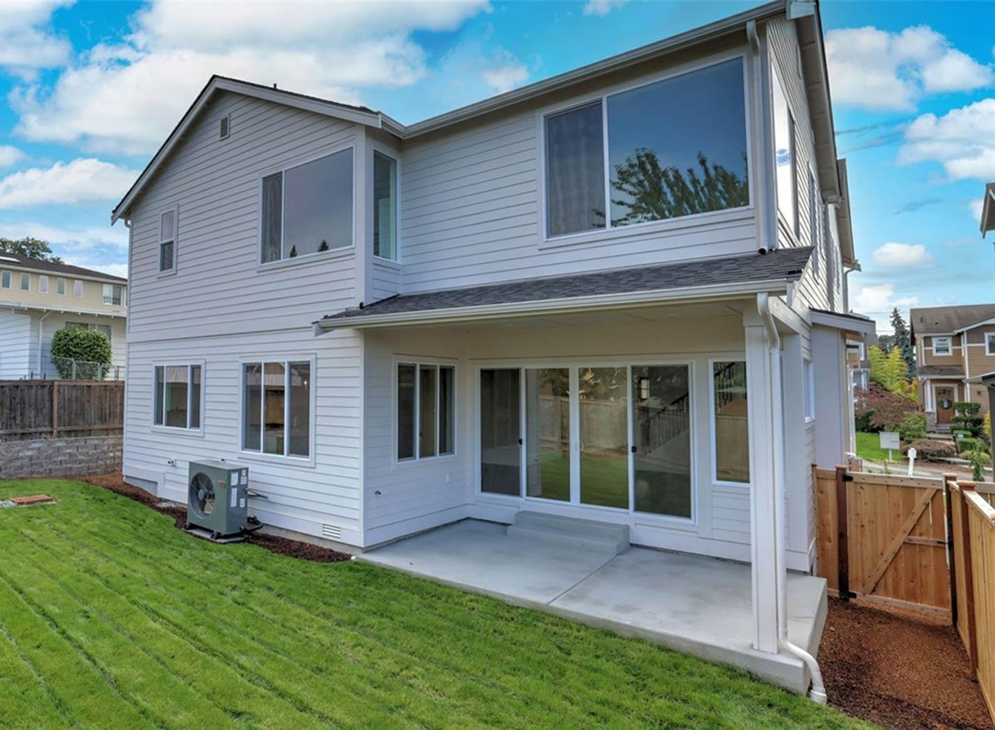 Two-story house plan exterior with white siding, multiple large windows, covered patio, and a pitched roof.