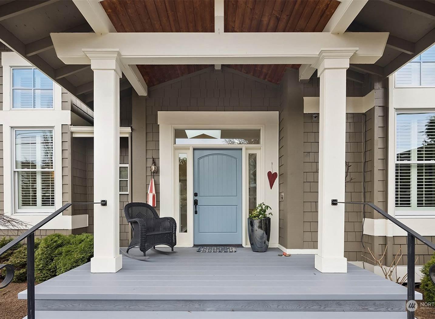 House plan exterior: Covered porch with wood soffits, white columns, and a blue arched-top entry door.