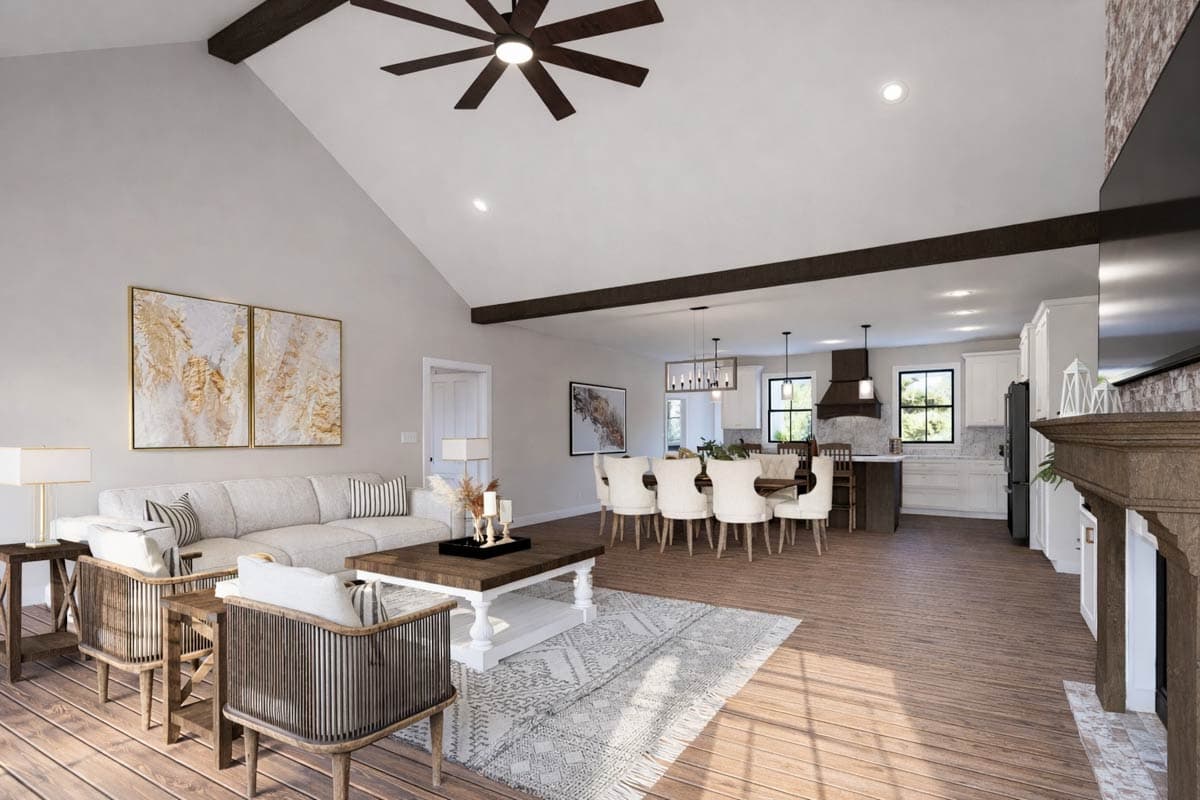 Open concept great room with vaulted ceiling, exposed beams, fireplace, dining area, and kitchen with island.