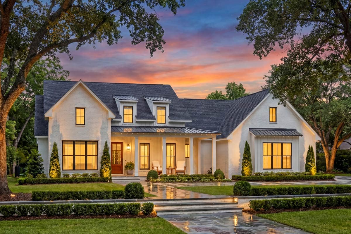 House plan exterior with white brick, gable dormers, a covered porch with white columns, and dark-framed windows.