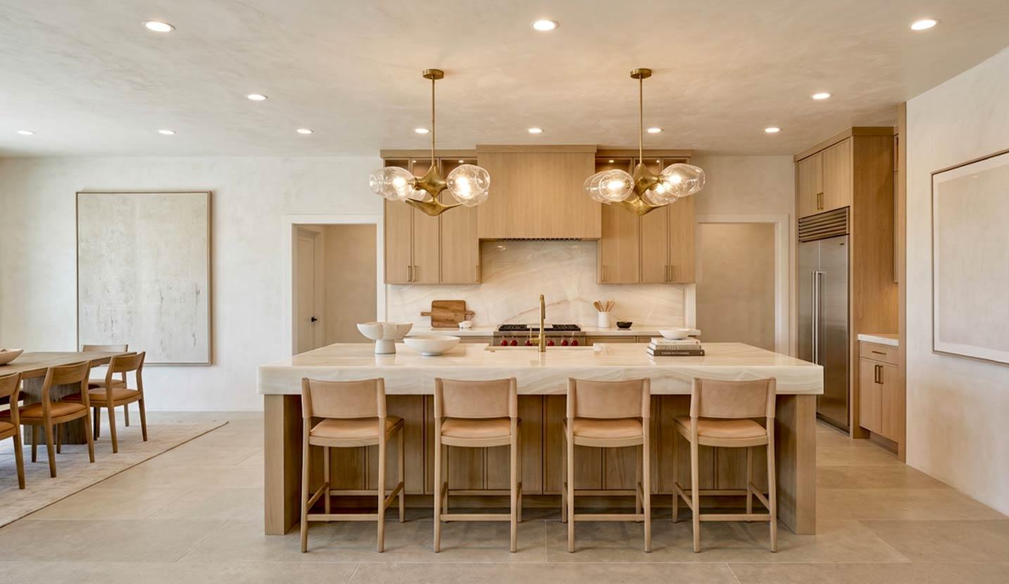 Modern kitchen with large island, wood cabinetry, marble countertops, and pendant lighting.