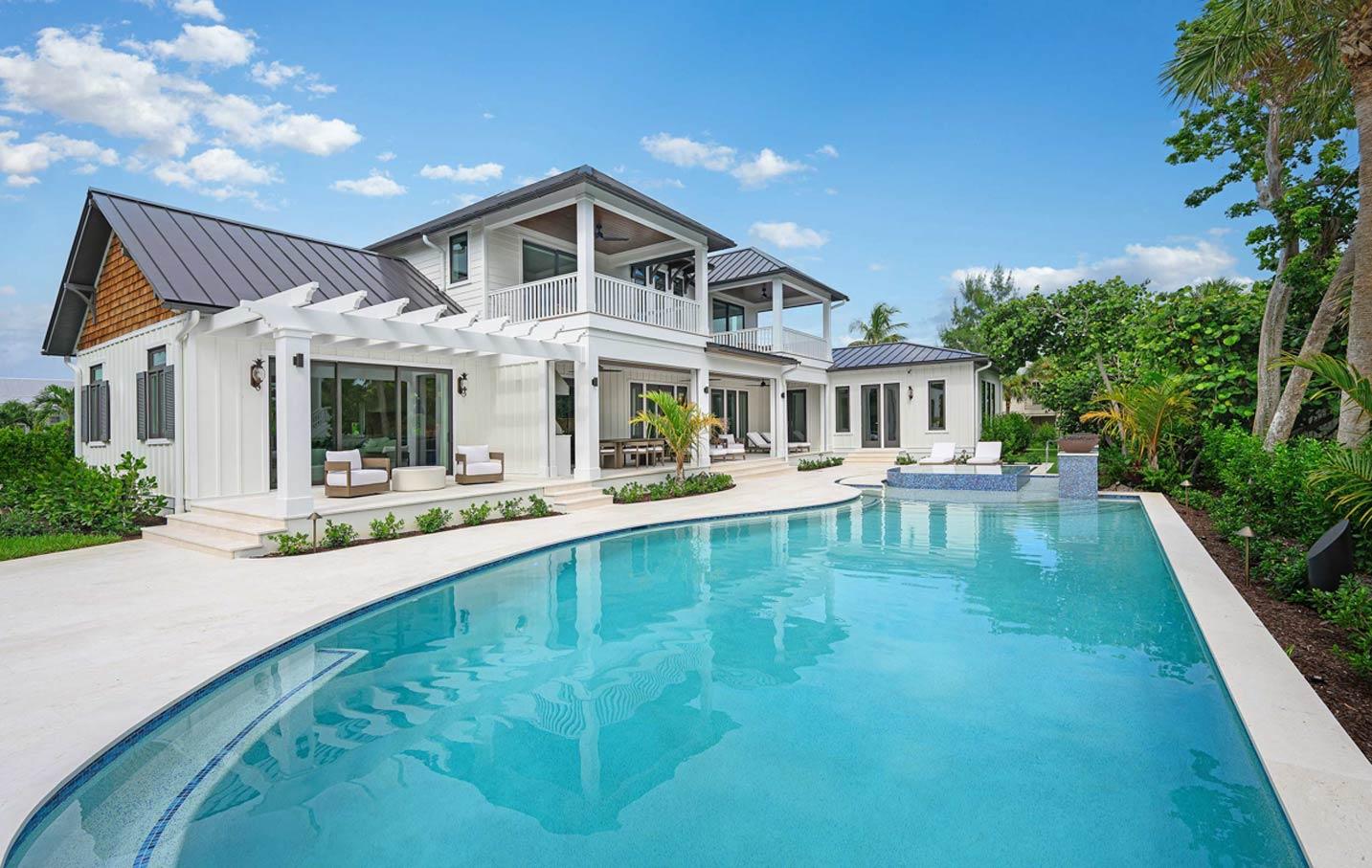 Modern Farmhouse style house plan exterior with white vertical siding, metal roofs, upper balconies, and a large swimming pool.