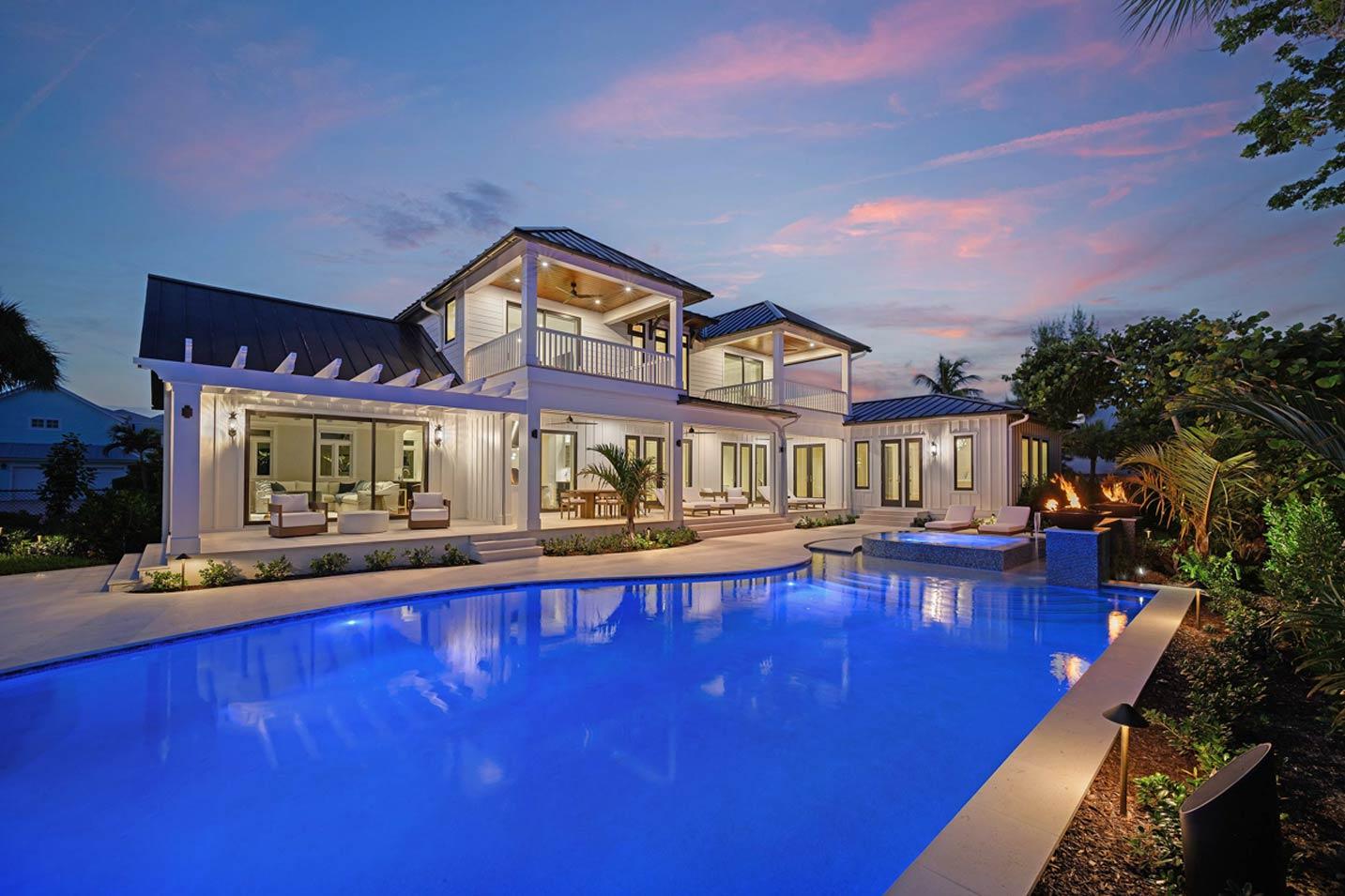 Modern coastal house plan exterior with two stories, gabled roof, balconies, and wraparound porch.