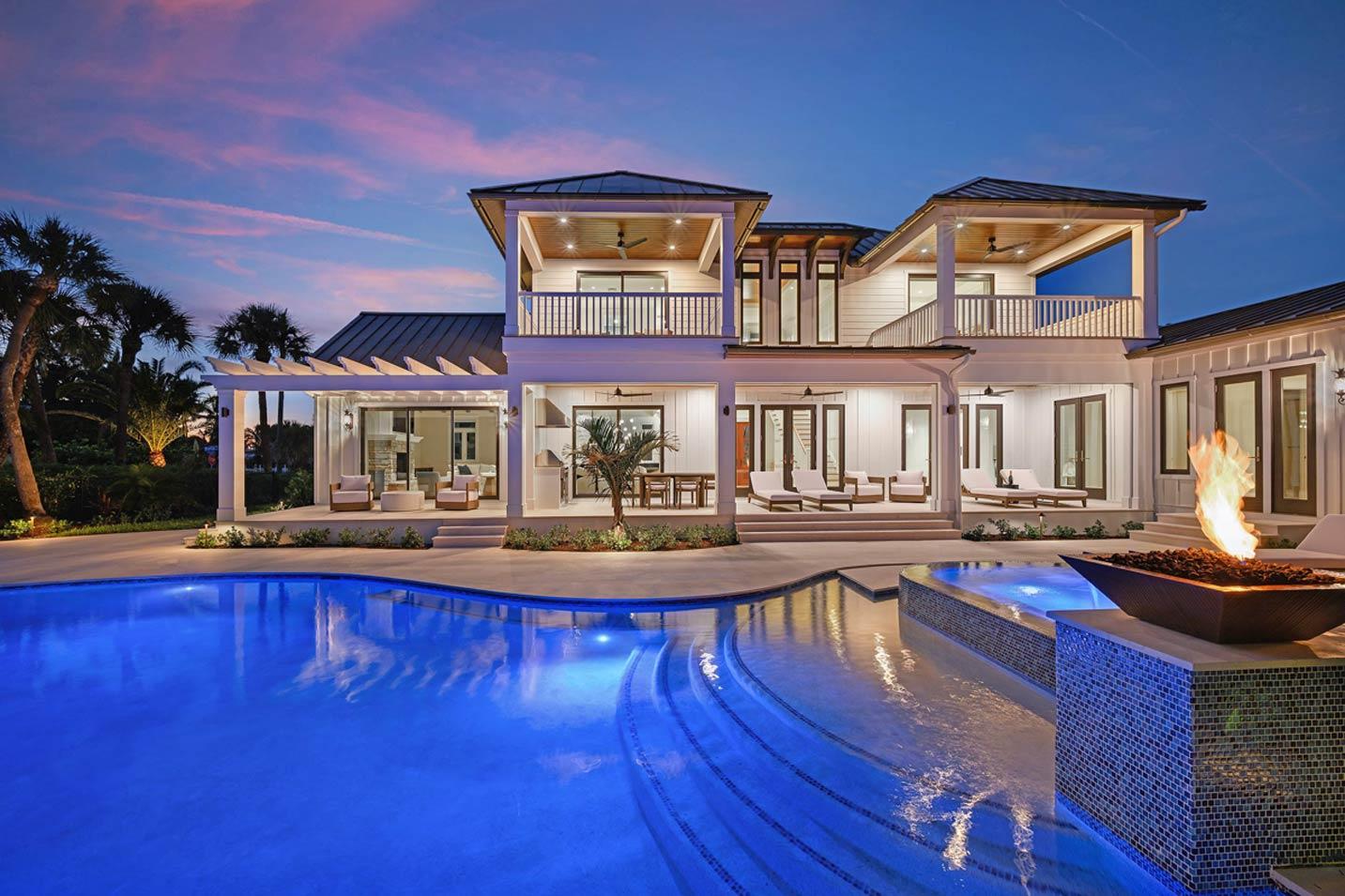 Modern coastal home exterior with multiple levels, balconies, covered patios, pool, and outdoor fireplace.