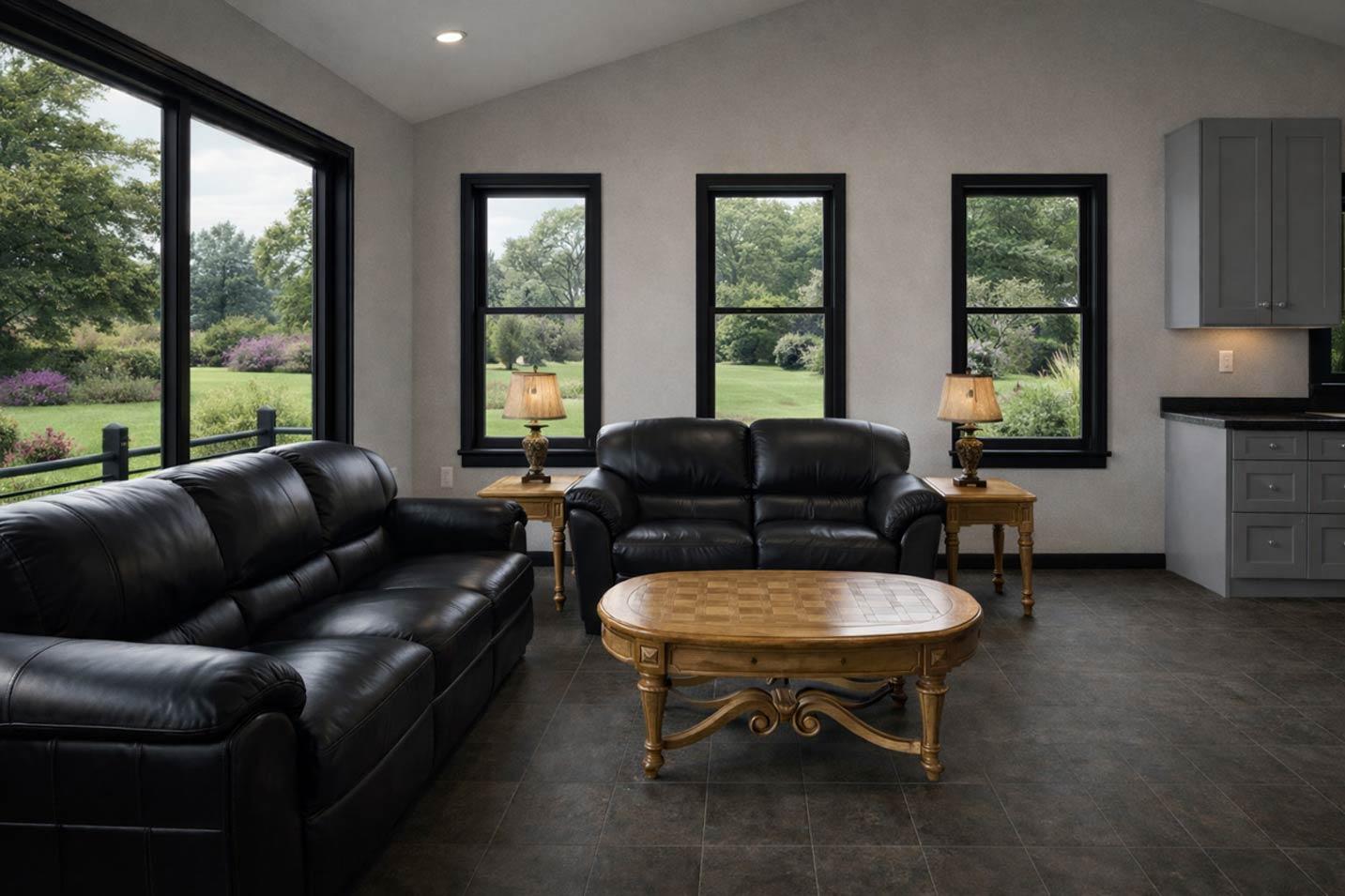 Living area with vaulted ceiling, black leather sofas, wood coffee table, and kitchen cabinetry visible.