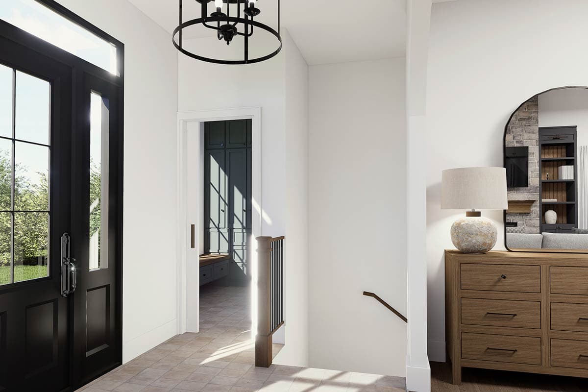 Interior entryway with black door, tile floor, view into mudroom, and staircase.