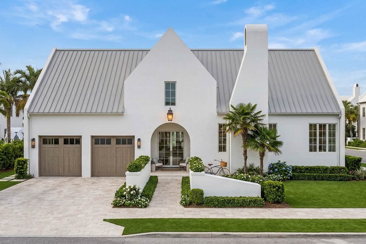 House plan exterior with a metal gable roof, arched entry, and a three-car garage.