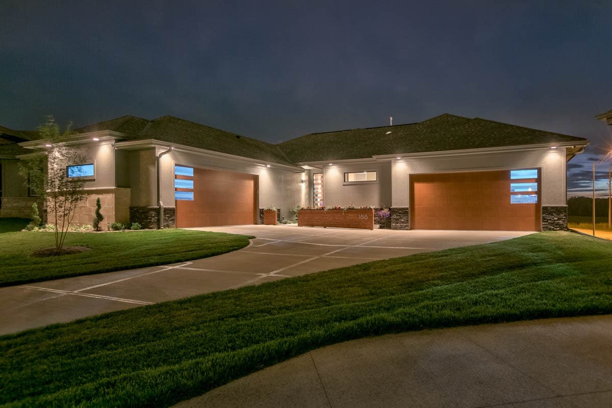 Modern house plan exterior with a U-shaped driveway, three garage doors, and horizontal windows.