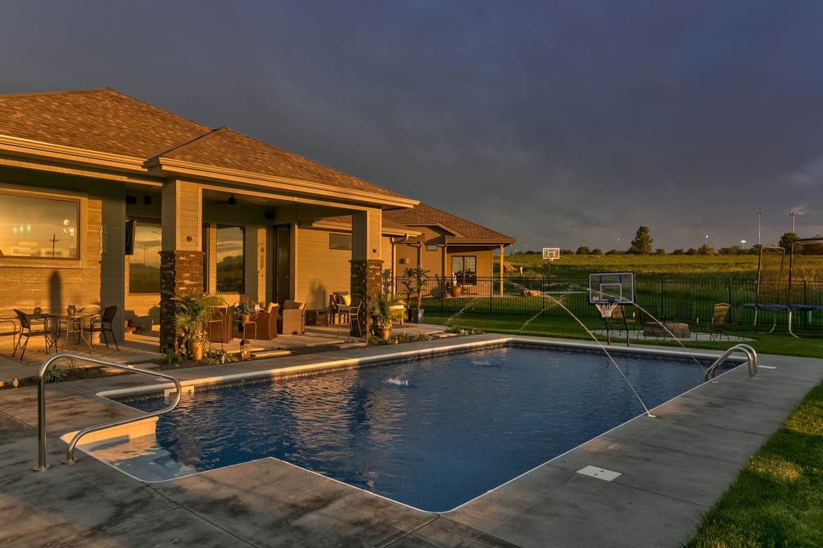 House plan exterior view of a single-story Modern Farmhouse with a covered patio, rectangular pool, and outdoor recreation.