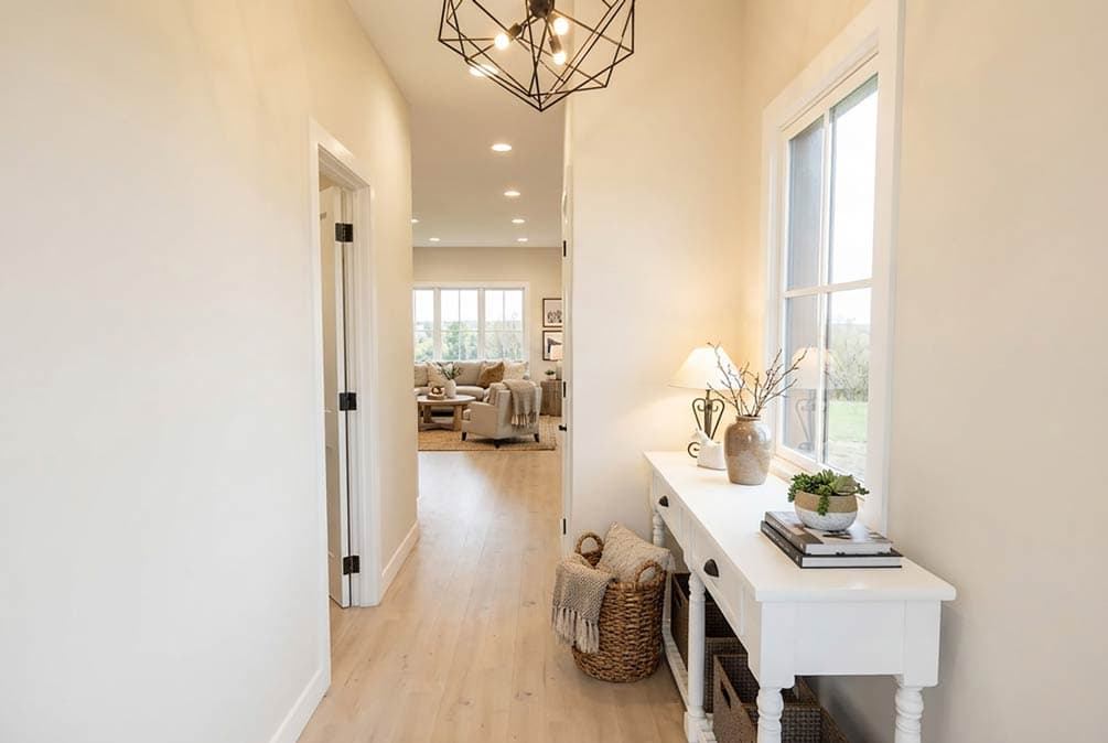 Interior view of a hallway leading to a living area, featuring a console table, basket, and geometric light fixture.