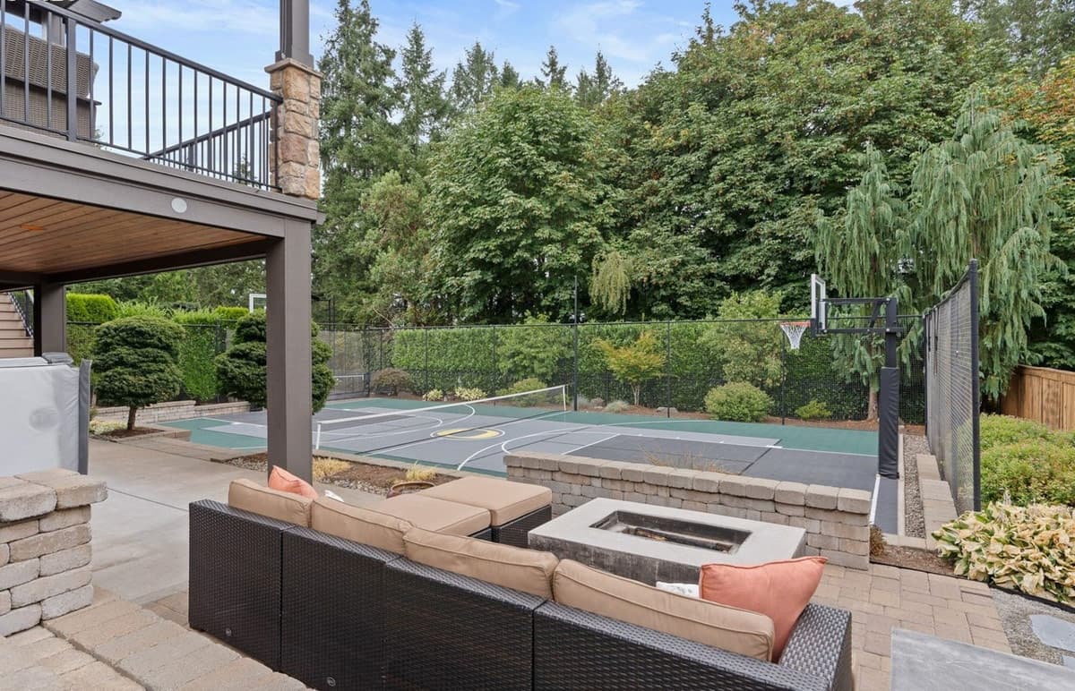 Backyard entertainment area with multi-sport court, basketball hoop, fire pit, and patio furniture.