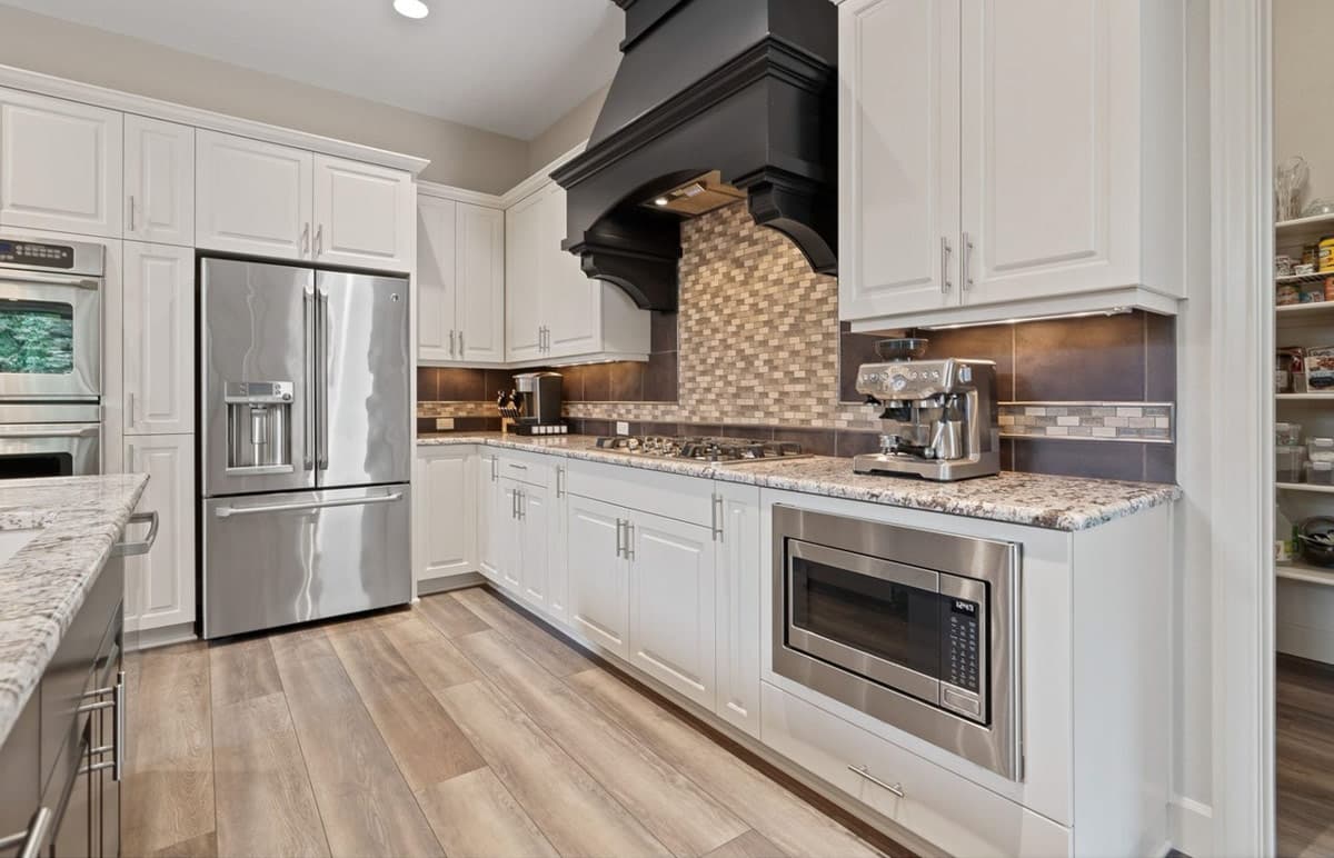 Kitchen with white cabinets, stainless steel refrigerator, gas range, and a built-in microwave.