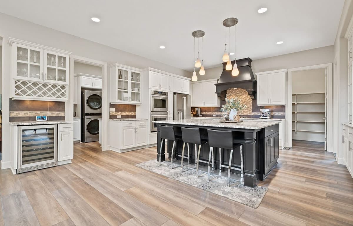 Kitchen featuring a large island with seating, wine fridge, built-in appliances, and a walk-in pantry.