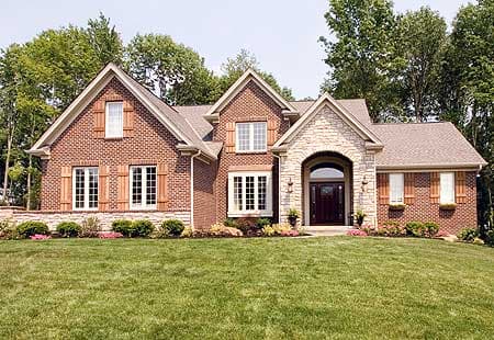 House plan exterior: Brick two-story home with stone arched entryway, multiple gables, and decorative shutters.