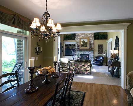 Dining area with wood table opens to living room with stone fireplace, built-in shelves and patterned sofa.