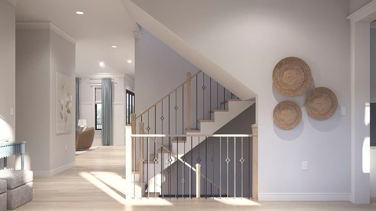Interior view of a house, showing a staircase with wood banisters and black metal spindles, leading to an upper level.