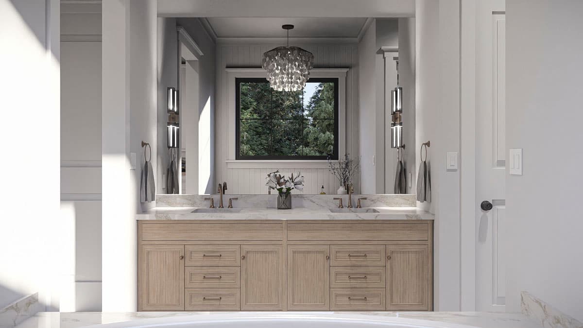Bathroom vanity with double sinks, marble countertop, wood cabinetry, and large window overlooking trees.