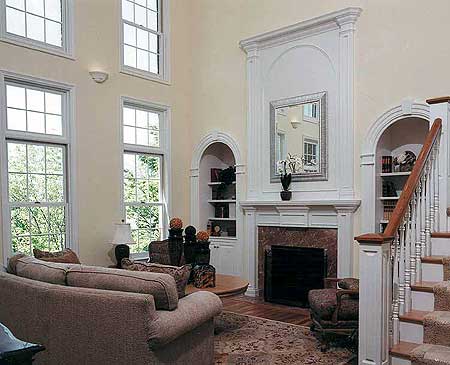 Interior view of a great room featuring a fireplace, built-in shelving, tall windows, and a staircase.