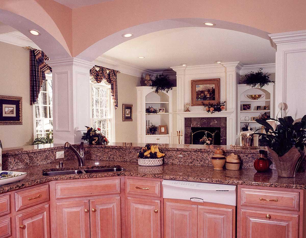 Kitchen featuring granite countertops, a double sink, wood cabinets, and a fireplace with built-in shelving.