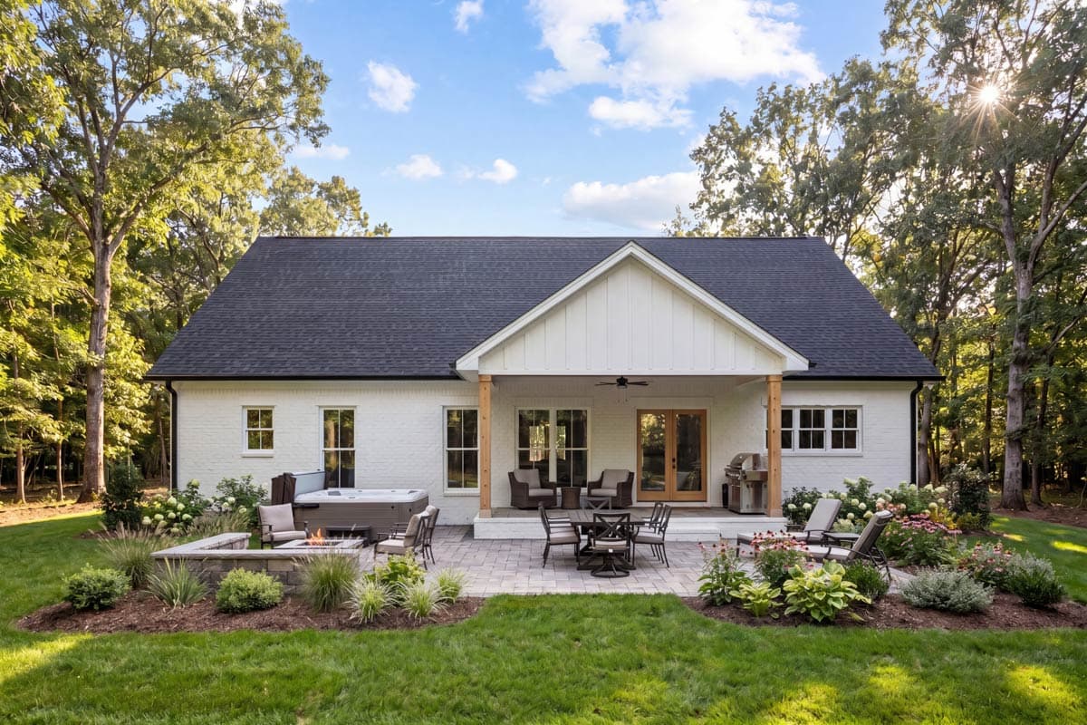 Modern Farmhouse house plan exterior with white brick, gable roof, covered porch with wood columns, patio, hot tub, and fire pit.