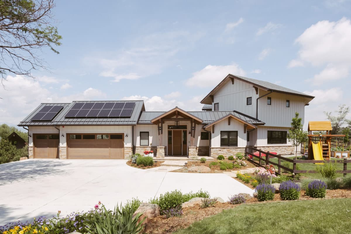 Modern Farmhouse house plan exterior with solar panels, dual garage doors, gabled rooflines, and stone accents.