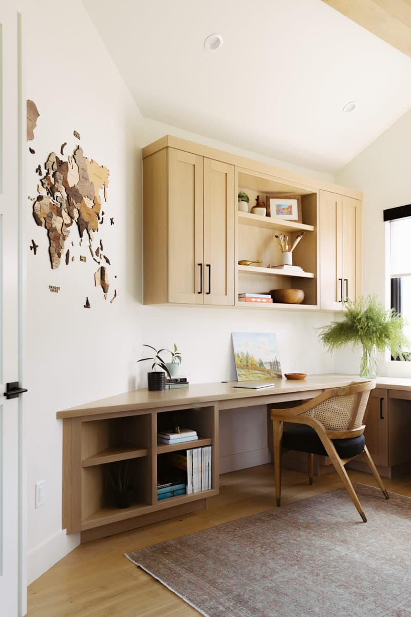 Interior: Corner desk with built-in wood cabinetry, open shelving, and a cane-backed chair.