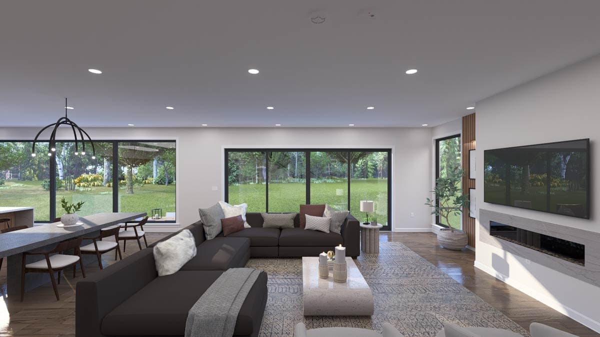 Great room with sectional sofa, fireplace, dining area, and large windows overlooking a backyard. Modern chandelier hangs above dining table.
