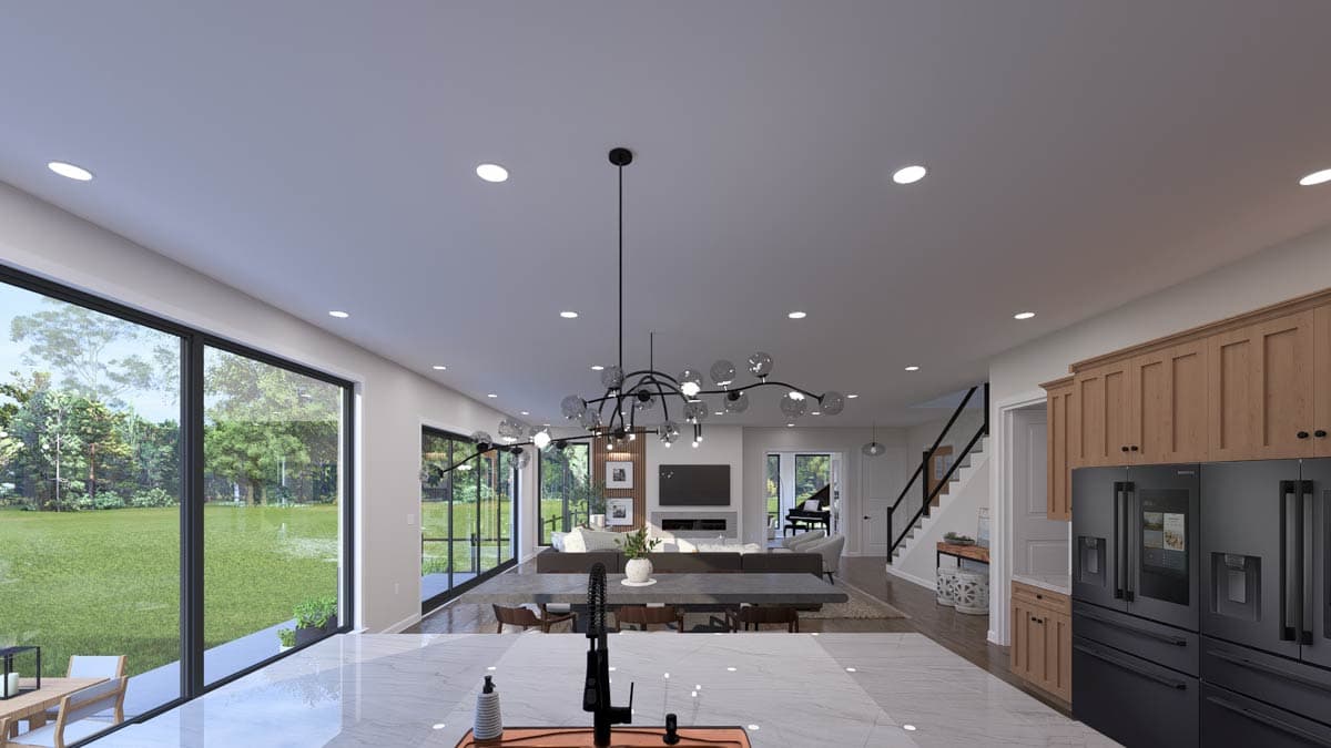 Open-concept living area with large windows, dining area, fireplace, piano, and modern kitchen with wood cabinetry and black appliances.