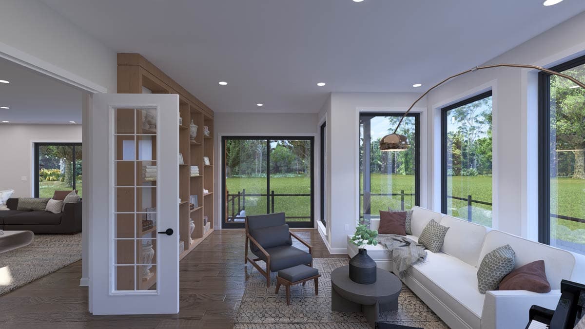 Interior view of a living room featuring a built-in bookshelf, large windows, and a sectional sofa.