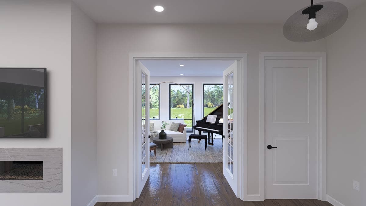 Interior view of a room with a grand piano, large windows, and double doors leading to a living area.