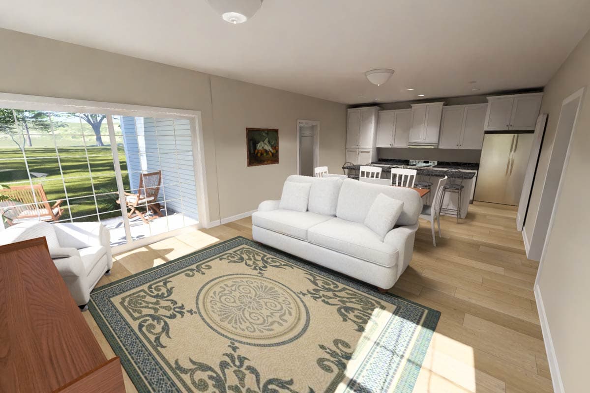Open concept living space with large sliding glass doors, white sofa, and kitchen with white cabinets and island.