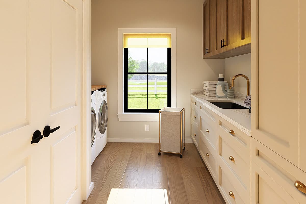 Laundry room with washer, dryer, sink, and ample cabinetry. Features a window overlooking a grassy field.