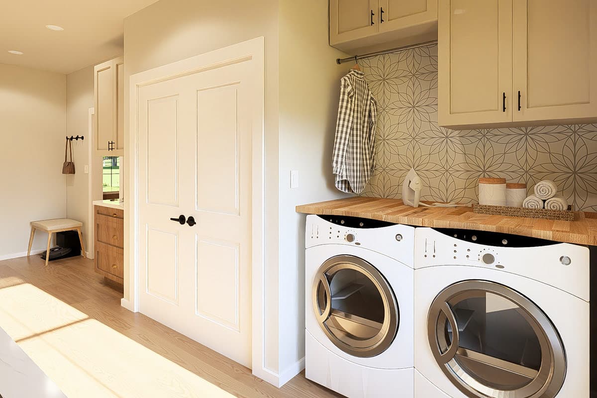 Laundry room with side-by-side washers, patterned tile backsplash, wooden countertop, cabinetry, and double doors.