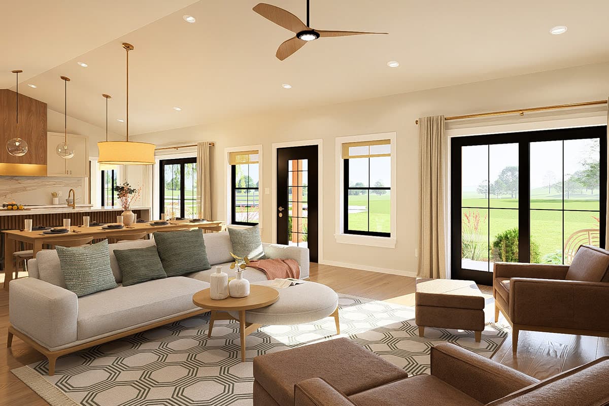 Open concept living area with sectional sofa, dining table, kitchen island, and large windows overlooking a yard.
