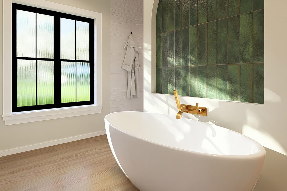 Freestanding bathtub with gold faucet, arched green tiled wall, and black casement window with textured glass.