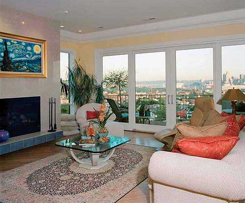 Living room with fireplace, large sliding glass doors, and a cityscape view.