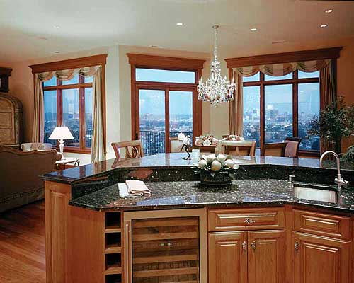 Interior view of a spacious kitchen with a granite island, wine cooler, sink, and large windows with city views.