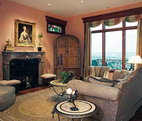 Living room with fireplace, ornate mantel, large arched cabinet, and bay windows overlooking a cityscape.