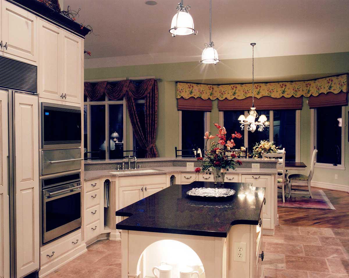 Kitchen with cream cabinetry, double ovens, dark granite island, and dining area with bay windows.
