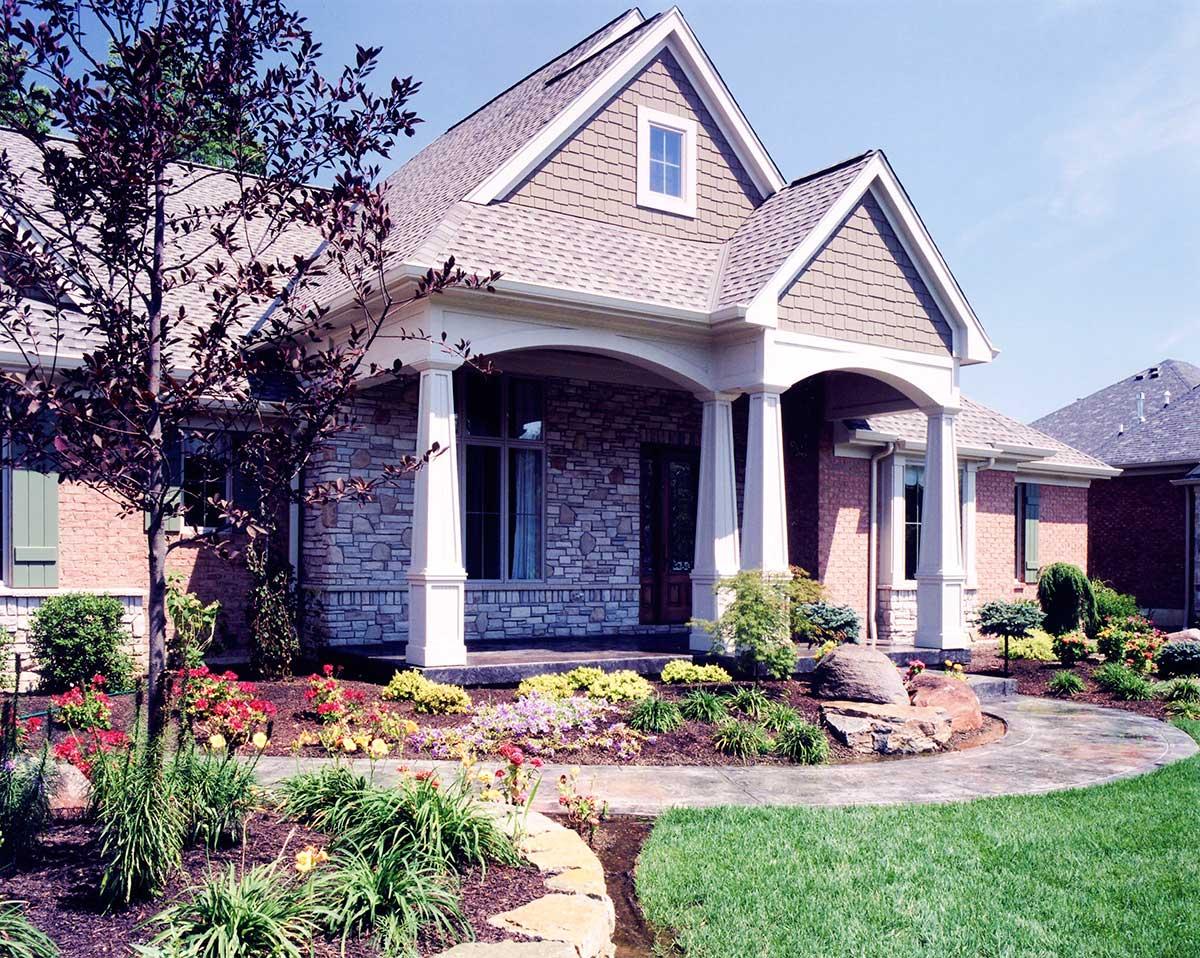 Craftsman house plan exterior with stone and brick facade, covered porch with columns, and dormer window.