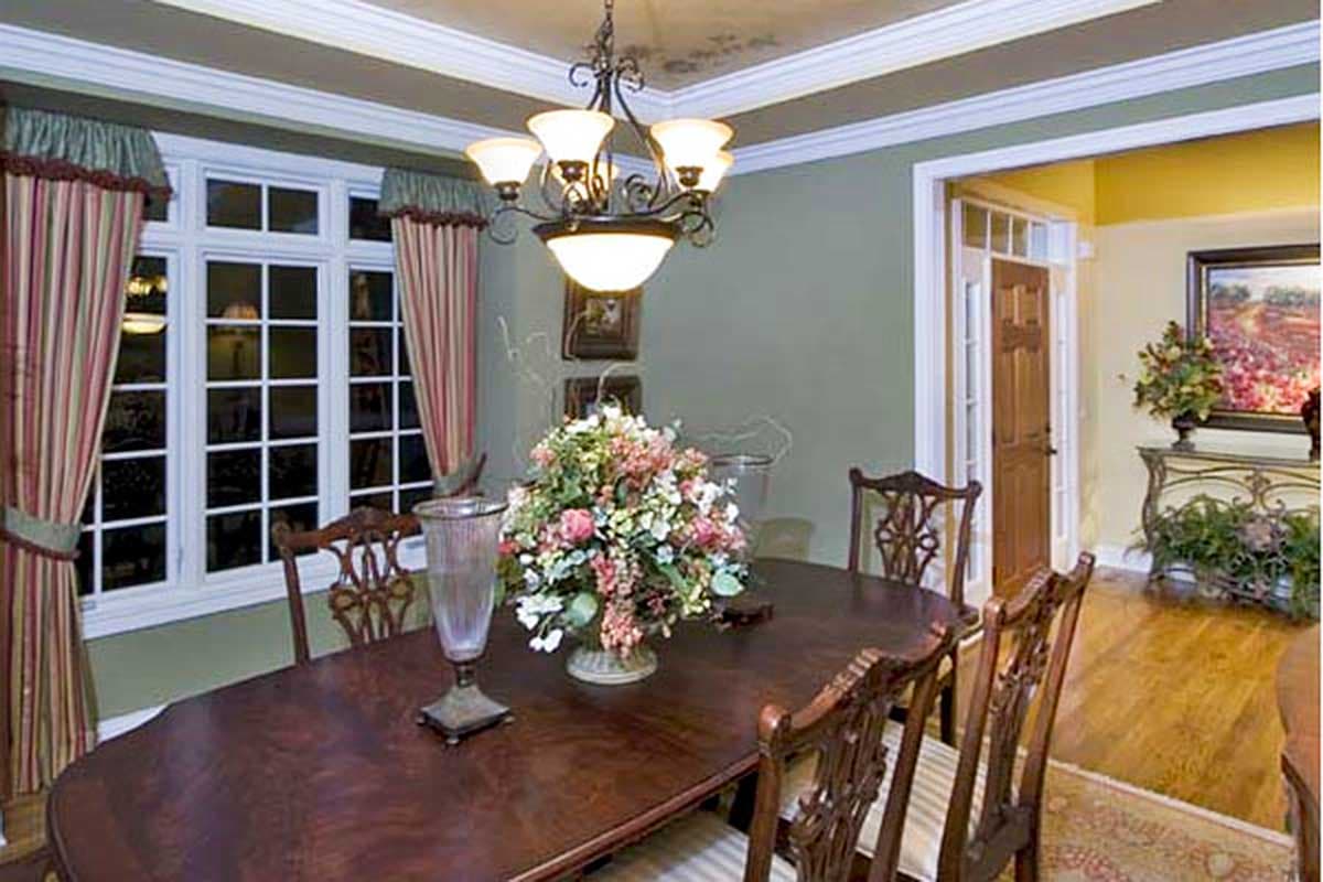Dining room interior rendering showing a wooden table, chairs, large window, and chandelier.